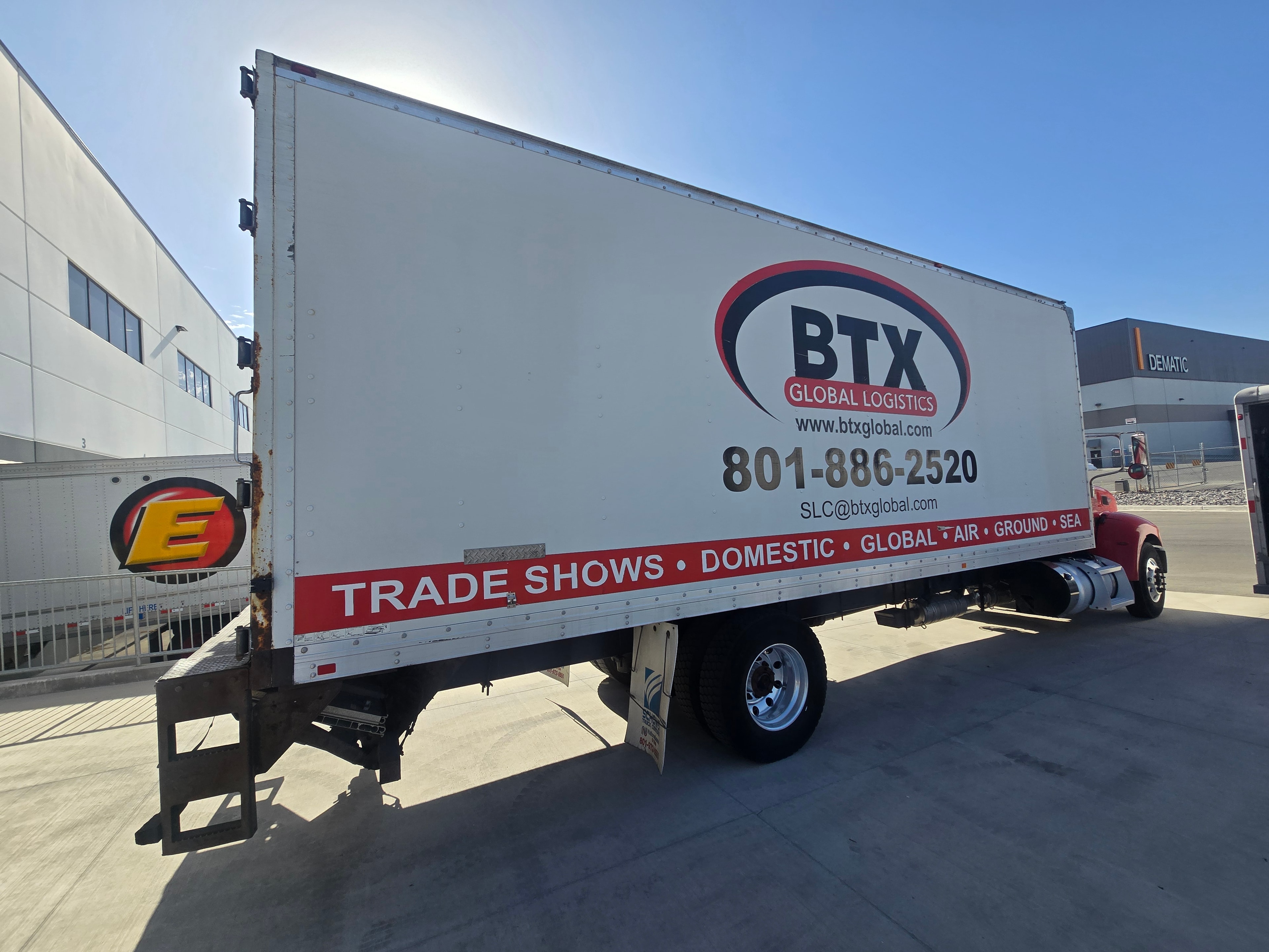 BTX Global Logistics box truck — rear side angle showing full graphics before decal removal