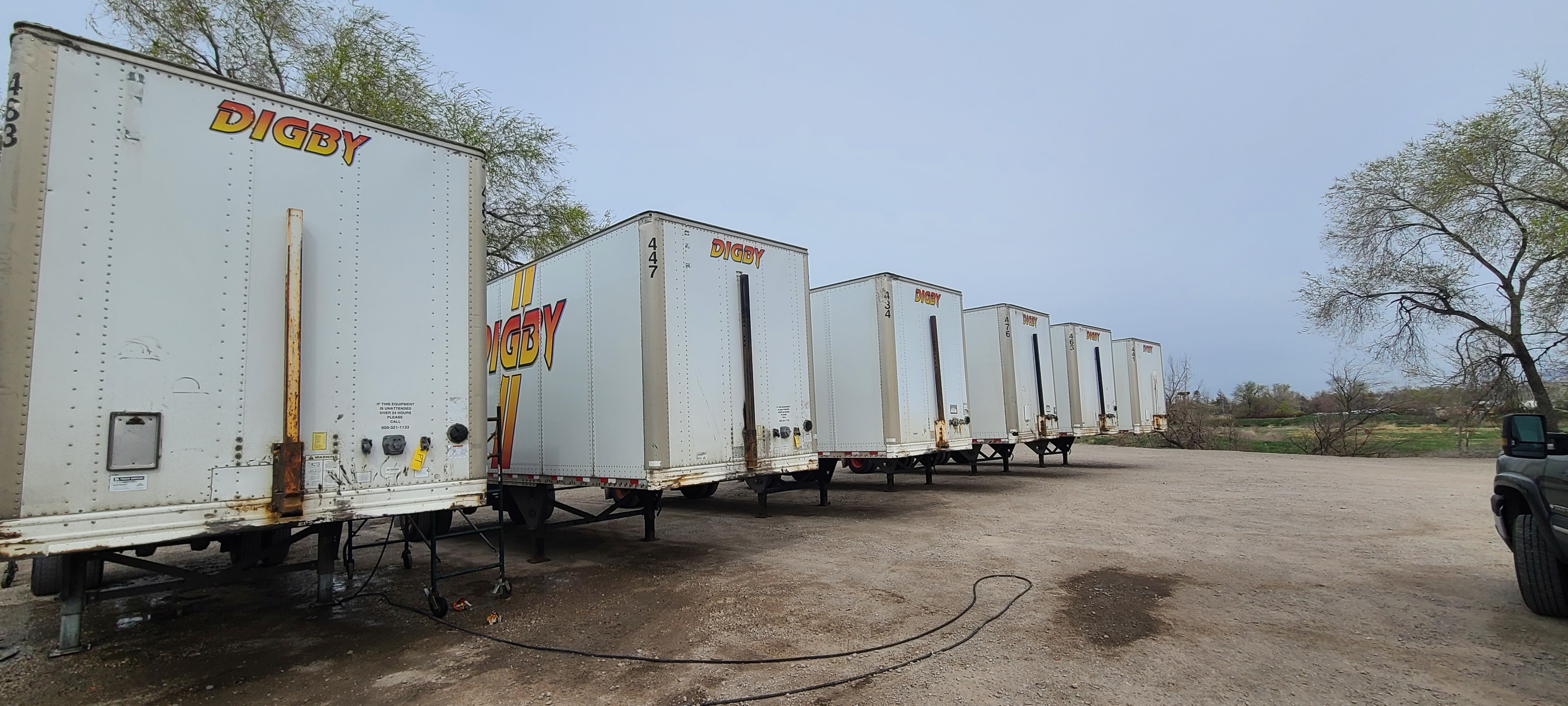 Digby pup trailers lined up in field — rear view showing aging vinyl graphics across the fleet