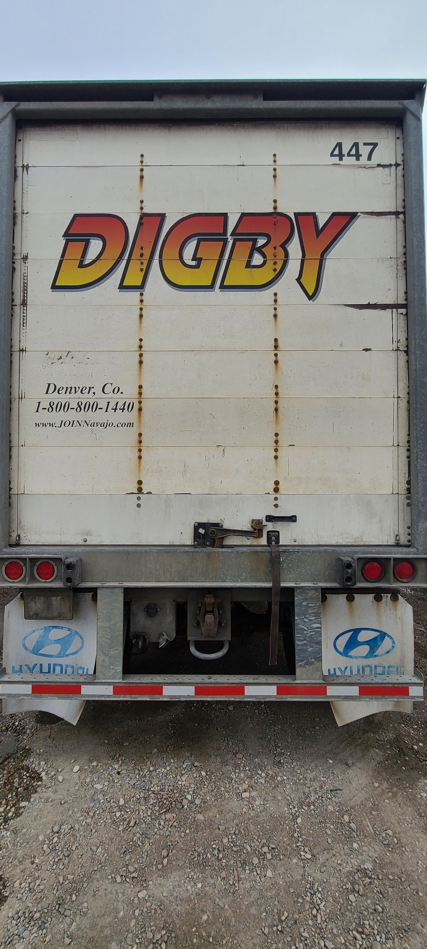 Close-up of Digby trailer #447 rear door — heavy rust staining and aging vinyl decal