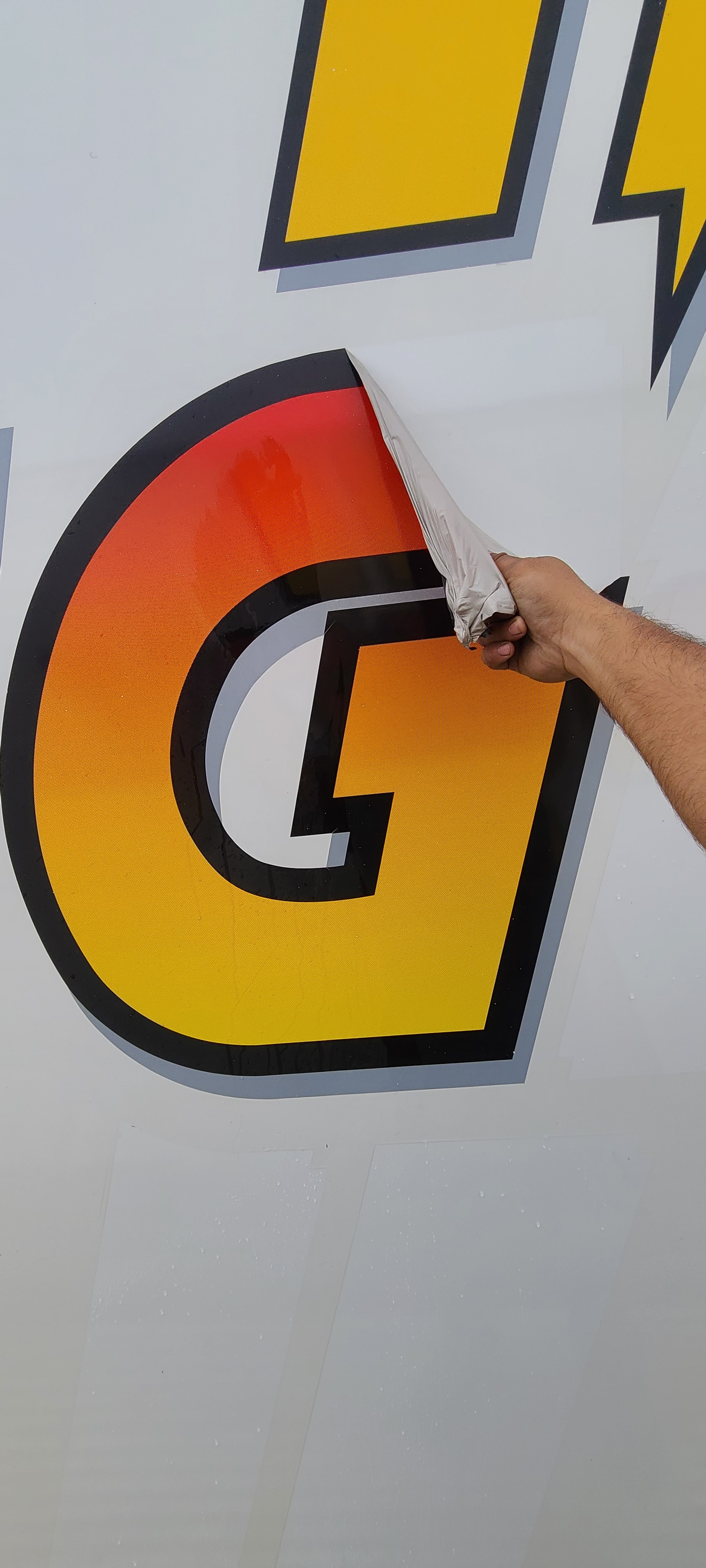 Technician hand-peeling large Digby fleet vinyl decal from commercial trailer panel — professional fleet de-identification service in Utah