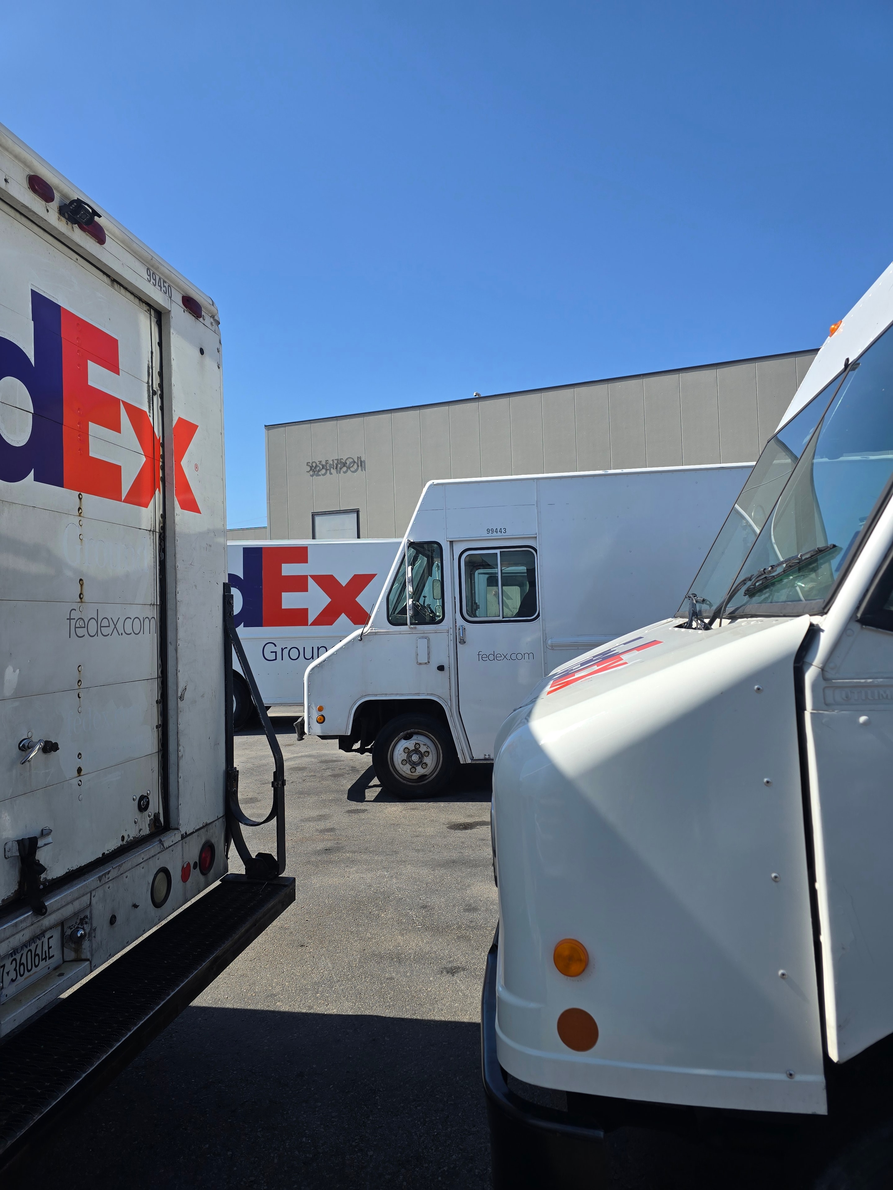 FedEx fleet overhead angle after de-identification — multiple step vans at Utah facility after rebranding project