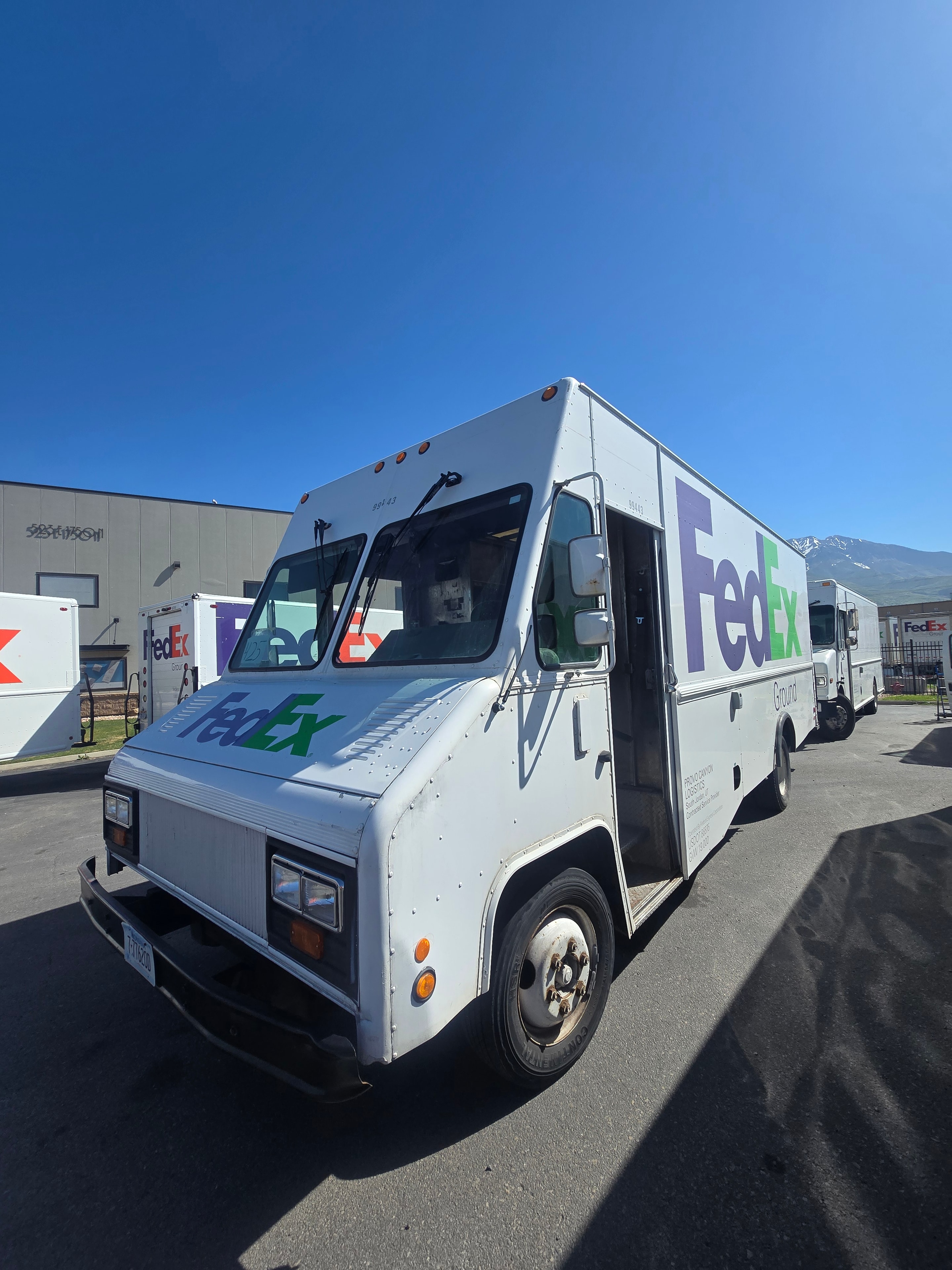 FedEx Ground step van fleet lineup — multiple branded vehicles at Utah facility before fleet de-identification project