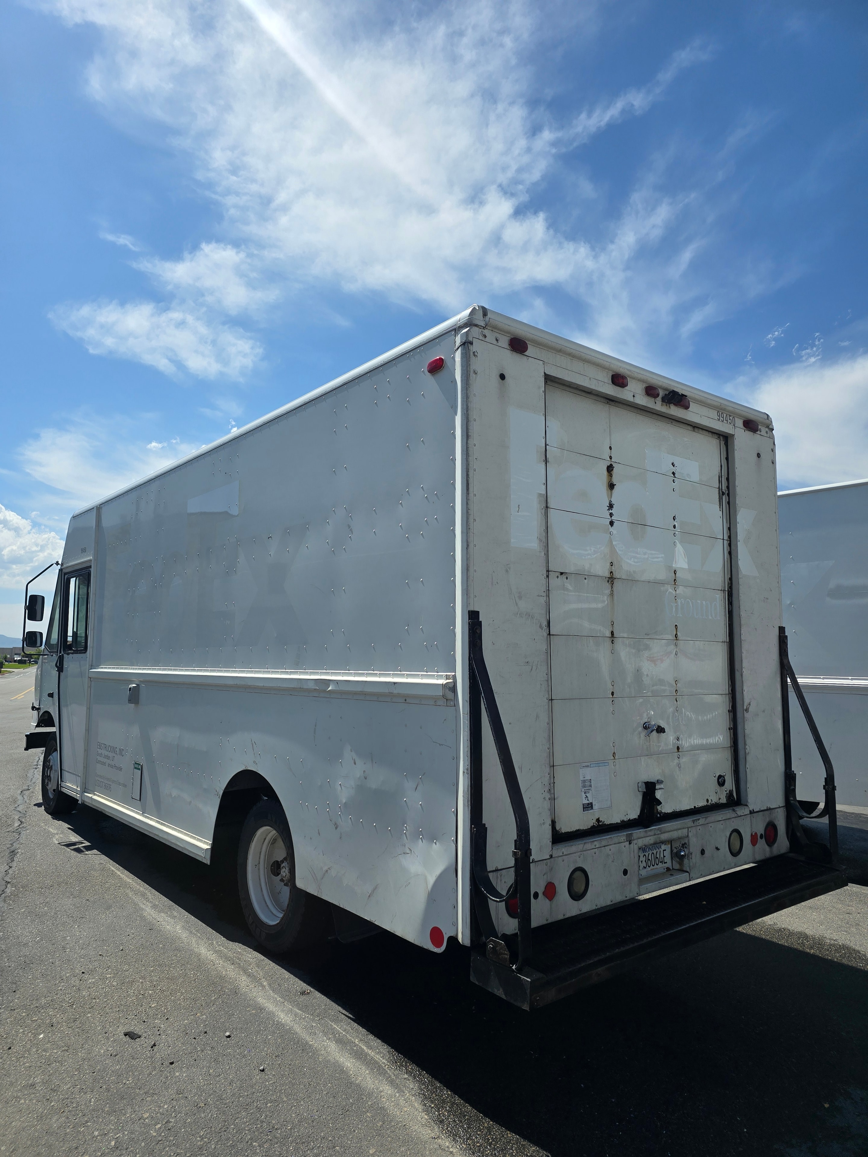 FedEx delivery van rear doors after decal removal — clean panels with adhesive ghosting visible during de-identification process
