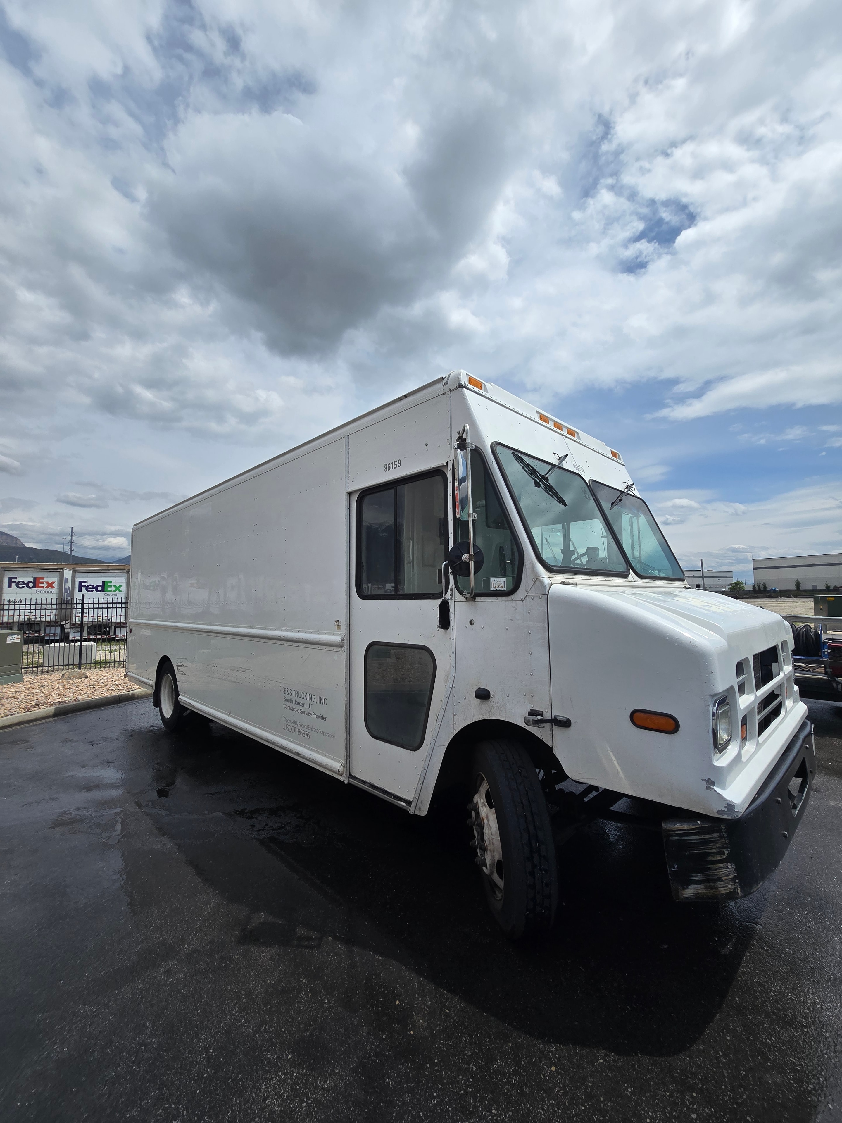 FedEx step van #6159 front quarter view during de-identification — decals removed, clean white panels, FedEx facility in background, Utah