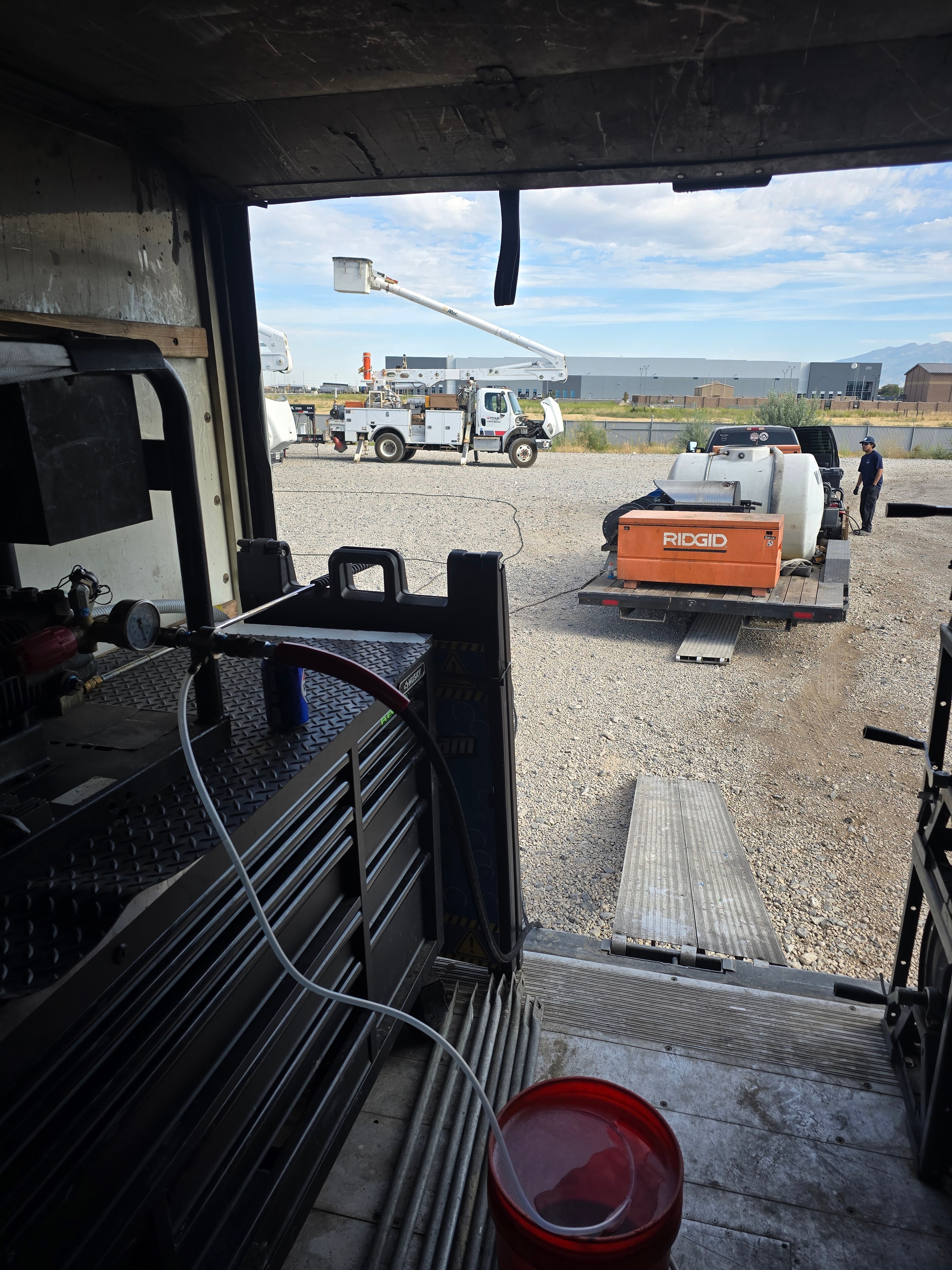 Titan fleet yard before washing — view from service truck bed showing RIDGID equipment and bucket trucks in background