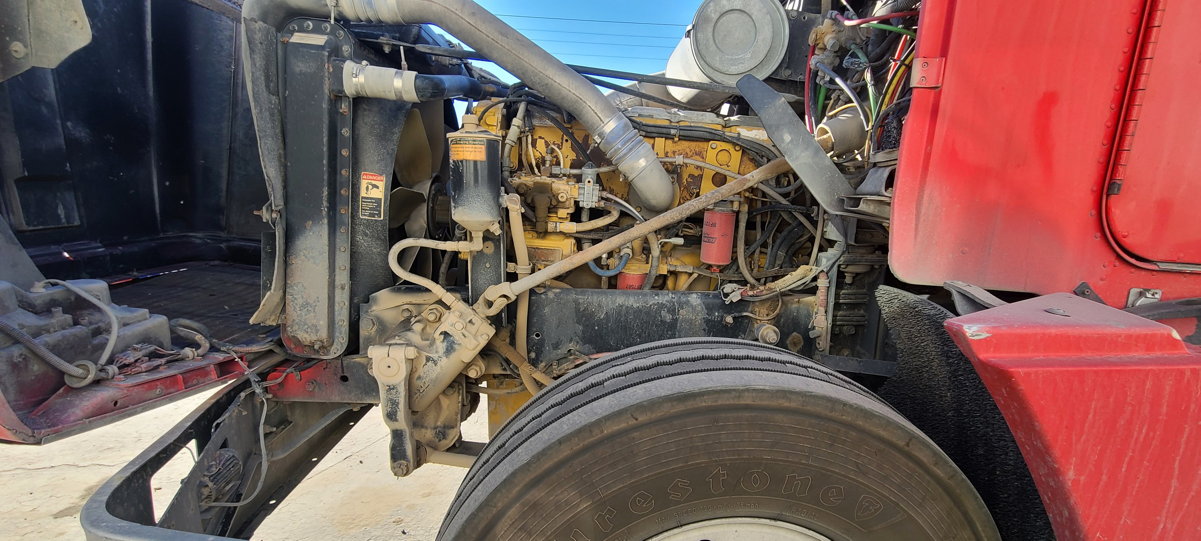 Red Kenworth engine bay — grease-coated filters and oil-soaked hoses, before degreasing Utah
