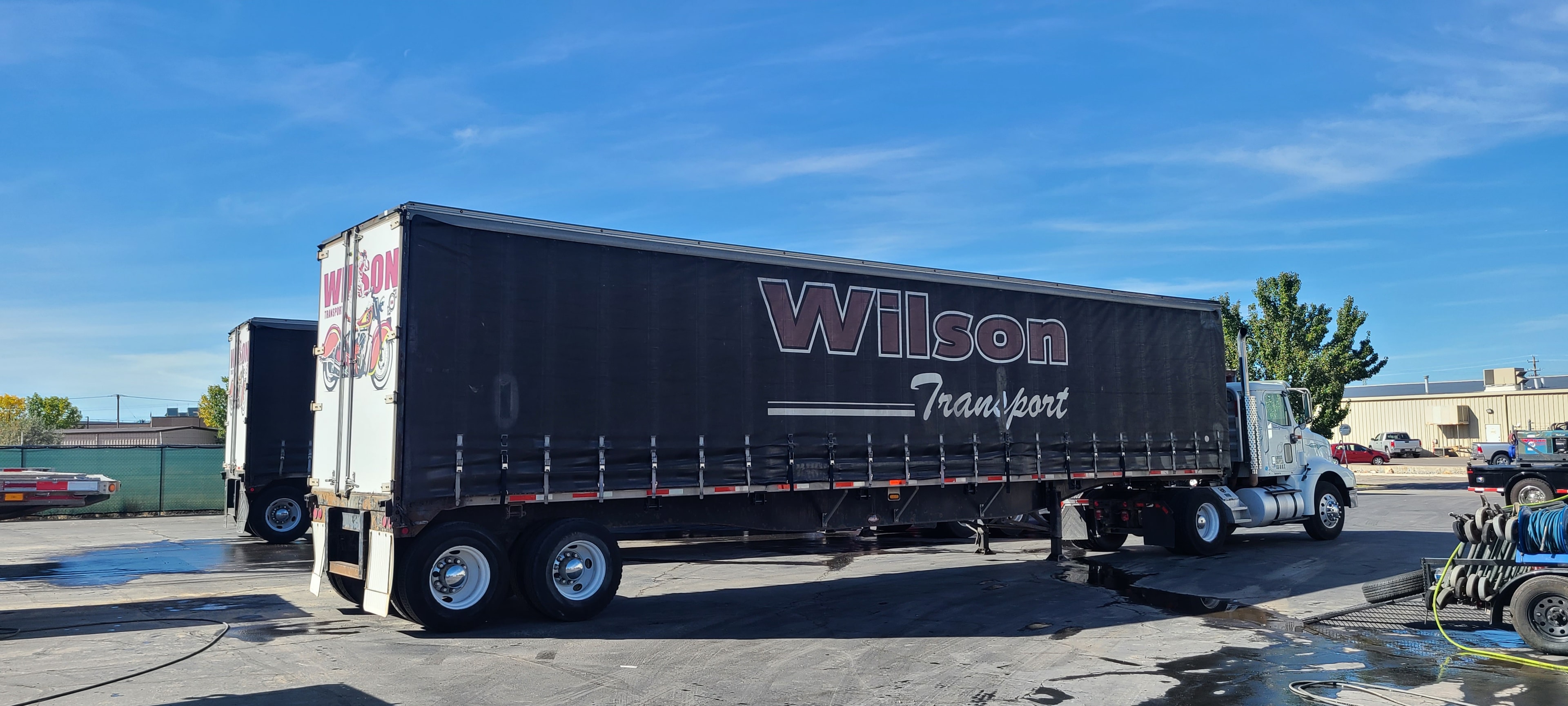 Wilson Transport curtain-side trailer — brand obscured by road grime, before washing